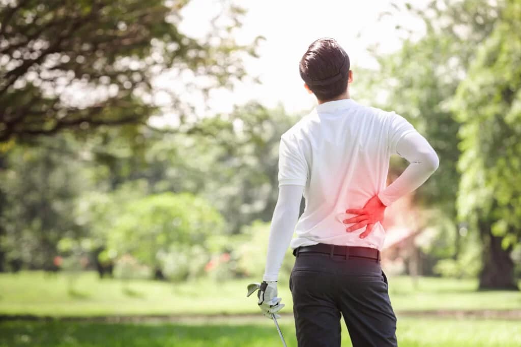 Golfer with lower back pain in a green park setting.