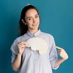 Woman holding and pointing to a paper brain cutout.