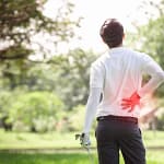 Golfer with lower back pain in a green park setting.